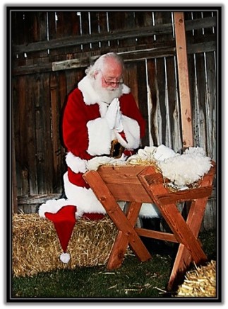 Papa Noel arrodillado ante el Niño Jesús